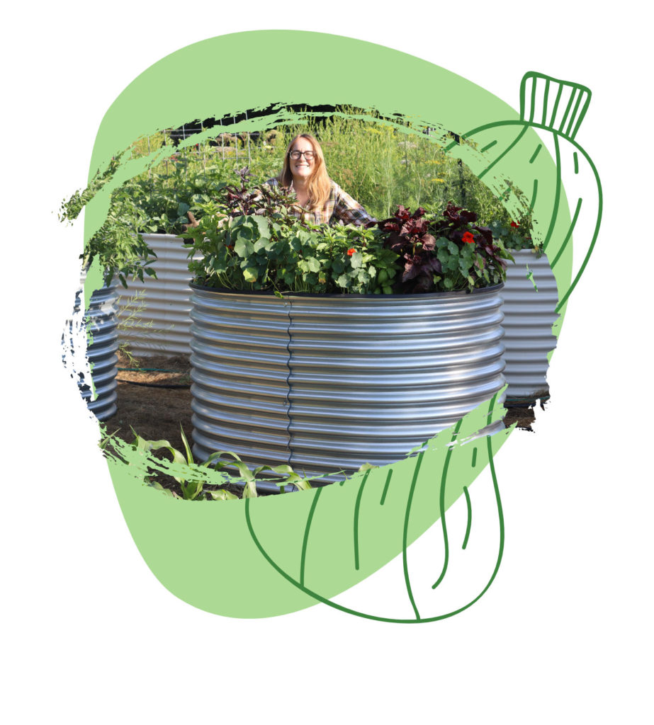 Founder Kerry standing smiling behind ergonomic garden tool, a tall raised garden bed. It is planted with herbs and flowers (basil and nasturtiums).