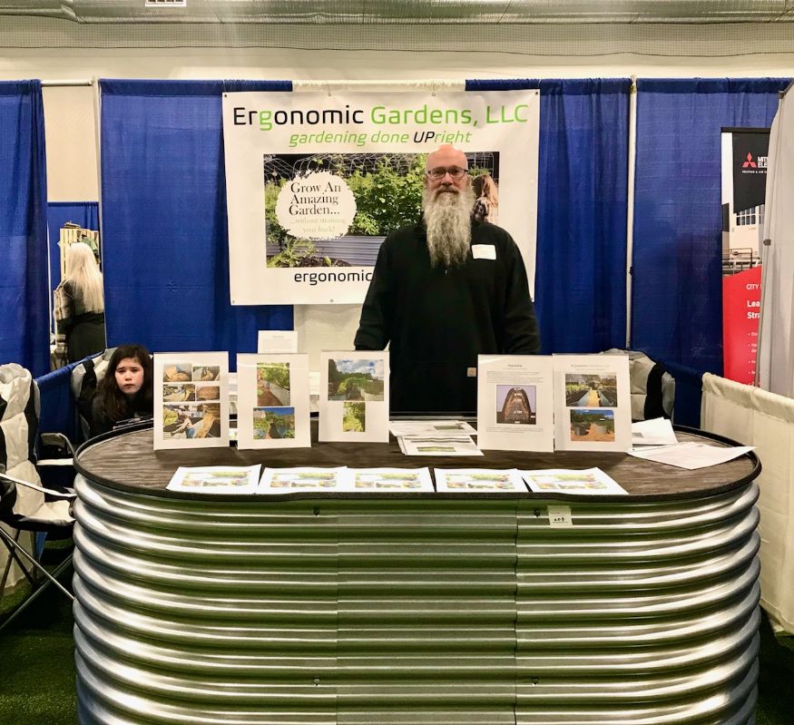 Founder, Chris with large elevated planter or raised garden bed (Evolution Garden) at Portland Green Home and Energy Show. Booth also contains Ergonomic Gardens, LLC banner and display materials